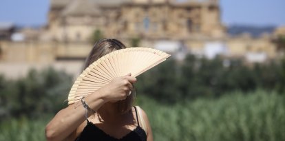 Una turista se abanica en el puente romano de Córdoba este viernes. El puente de agosto comienza con España inmersa en una larga ola de calor