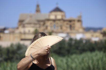 Una turista se abanica en el puente romano de Córdoba este viernes. El puente de agosto comienza con España inmersa en una larga ola de calor