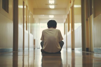 Un adolescente pensativo en un pasillo vació de una escuela.