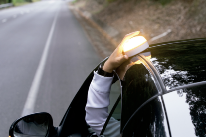 Una baliza V16 en el techo de un coche estacionado de forma irregular a causa de un percance.