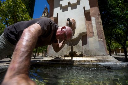 Un hombre se refresca en una fuente este sábado, una jornada marcada por la ola de calor que afecta a numerosas partes del país.