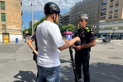 Un agente informando a un joven que circula en patinete.