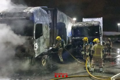 Dos bomberos trabajando para extinguir las llamas del incendio que ha quemado dos camiones en Tarragona