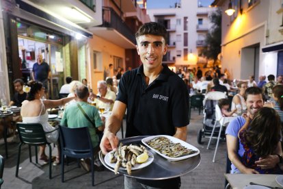 Un camarero muestra algunos de los platos de Bar Sport.