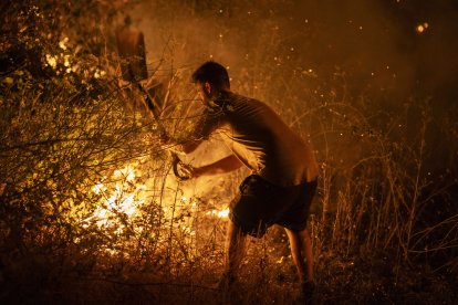 Un vecino trabaja la madrugada de este domingo en labores de extinción del incendio forestal de A Rúa (Ourense)