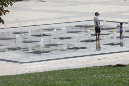 Dos personas se refrescan en una fuente este domingo durante la ola de calor