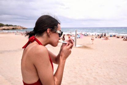 Una mujer encendiéndose un cigarrillo en la playa.