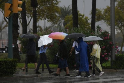 Varias personas se protegen de la lluvia en Palma de Mallorca, donde este martes ha llegado un temporal de lluvia y viento
