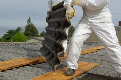 Un operario retira restos de amianto de un tejado.