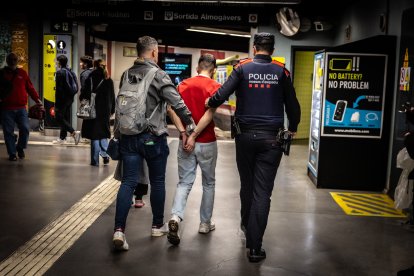 Dos agentes detienen a un hombre en el metro de Barcelona durante la operación 'Kanpai'