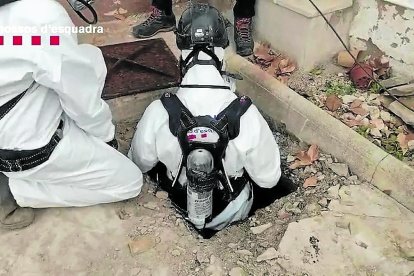 Dos agentes de los Mossos entrando en la fosa séptica donde se hallaba el cuerpo del desaparecido.