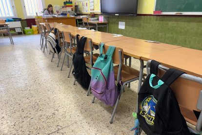 Una imagen de un aula con las mochilas de alumnos colgadas en el respaldo de la silla.