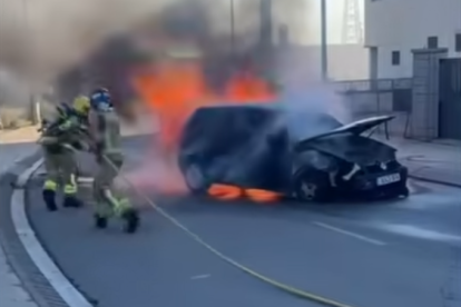Dos bomberos trabajan para acabar con el fuego de un coche en Roda de Berà