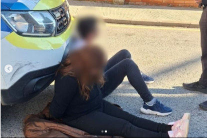 Los dos sospechosos, esposados junto al vehículo policial.