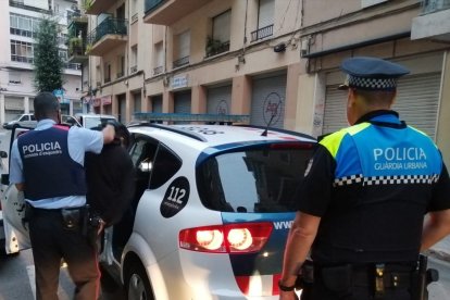 Uno de los diez detenidos en la operación policial entrando a un coche de Mossos.