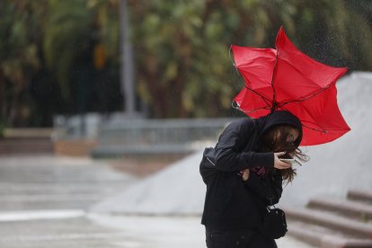 Una mujer lucha contra el fuerte viento.