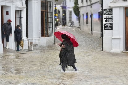 Una vecina de Grazalema (Cádiz) camina por una calle inundada debido a las intensas lluvias