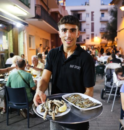 Un camarero muestra algunos de los platos de Bar Sport.