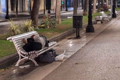 Una persona durmiendo el martes por la noche en un banco de la Rambla Nova.