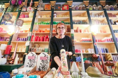 3. Xavier enseña un cirio de Santa Tecla, con una de las coloridas estanterías de la tienda al fondo.