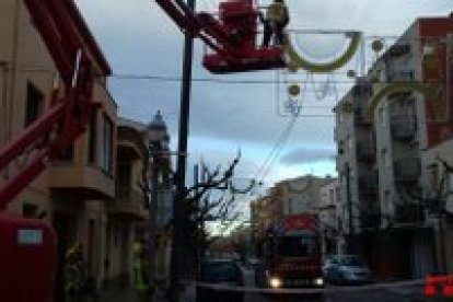 Los bomberos retirando las luces de Navidad de la calle Reus, en La Pobla de Mafumet.