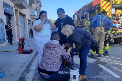 La vecina del piso incendiado, preocupándose por su perro. Le han dado oxígeno para reanimarlo.