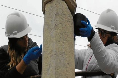 Les restauradores Olga Schmid i Marina Ramisa instal·lant la creu a Ulldecona.