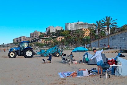 Dos grupos de personas acampadas en el Miracle mientras pasa a su lado la máquina de la limpieza.