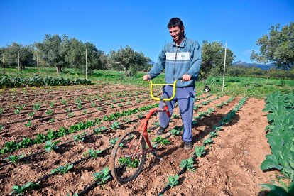 Adrià Palau, amb la bicicleta que ha adaptat per poder treballar més fàcilment la terra, a Vilanova d’Escornalbou.