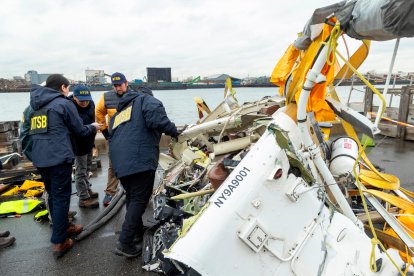 Miembros de la NTSB analizando la cabina del helicóptero recuperada del río.