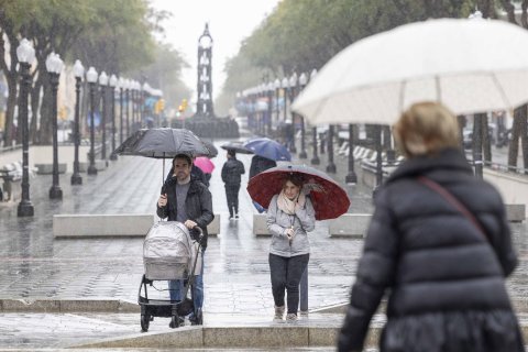 Gente paseando por la Rambla Nova de Tarragona bajo la lluvia.