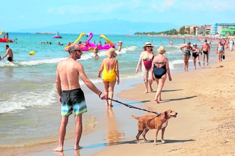 Un hombre pasea a su perro en la playa de Ponent de Salou.