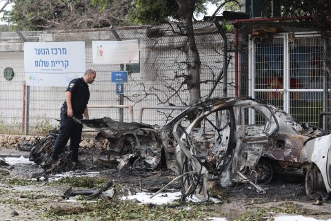 Un policía israelí inspecciona los restos de un vehículo incendiado después de que Israel interceptara un misil balístico de Irán, este domingo, en Tel Aviv.