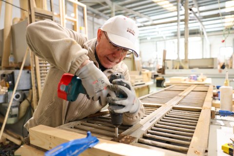 Un trabajador de Moix ebenisteria apretando un tornillo de una pieza durante su jornada de trabajo en el taller de la empresa en Reus.