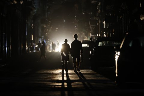 Personas caminan por una calle sin electricidad.