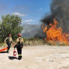 Dos bomberos al lado de una llamarada del incendio.