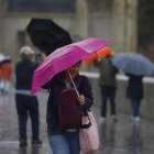 Una mujer intenta mantener su paraguas abierto bajo una intensa lluvia con viento.