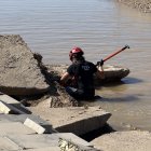 Un bombero mira si puede haber algo entre unas rocas.
