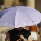Una turista se protege del sol con un paraguas. El puente de agosto comienza con España inmersa en una larga ola de calor