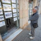 Un ciudadano mira pisos en venta y en alquiler ante una inmobiliaria