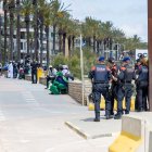 Agentes de Policía Local y Mossos d'Esquadra montando guardia frente a un grupo de manteros.
