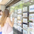 Dos personas miran los anuncios en el escaparate de una inmobiliaria en Tarragona.
