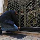 Fotografía de archivo de un trabajador bajando la persiana de un negocio.