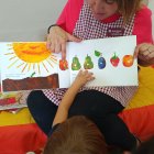 Una educadora de una Llar d'Infants explica un cuento a un niño.