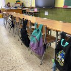 Una imagen de un aula con las mochilas de alumnos colgadas en el respaldo de la silla.