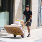 Un repartidor transporta paquetes en uno de los picos de más calor en el Puente de Piedra de Girona