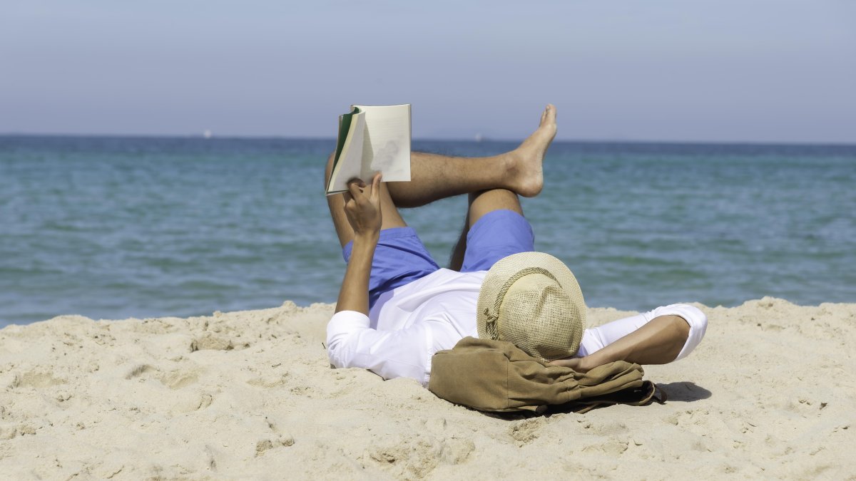 Un hombre leyendo en la playa.​​