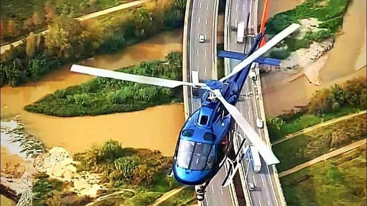Uno de los helicópteros sobrevolando una de las entradas a Barcelona por encima del río Llobregat.​