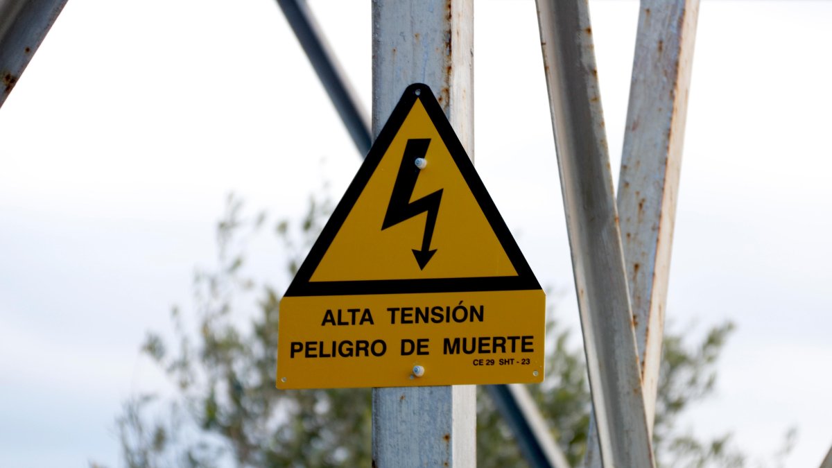 Cartel en el que se advierte del peligro de alta tensión en una de las torres eléctricas