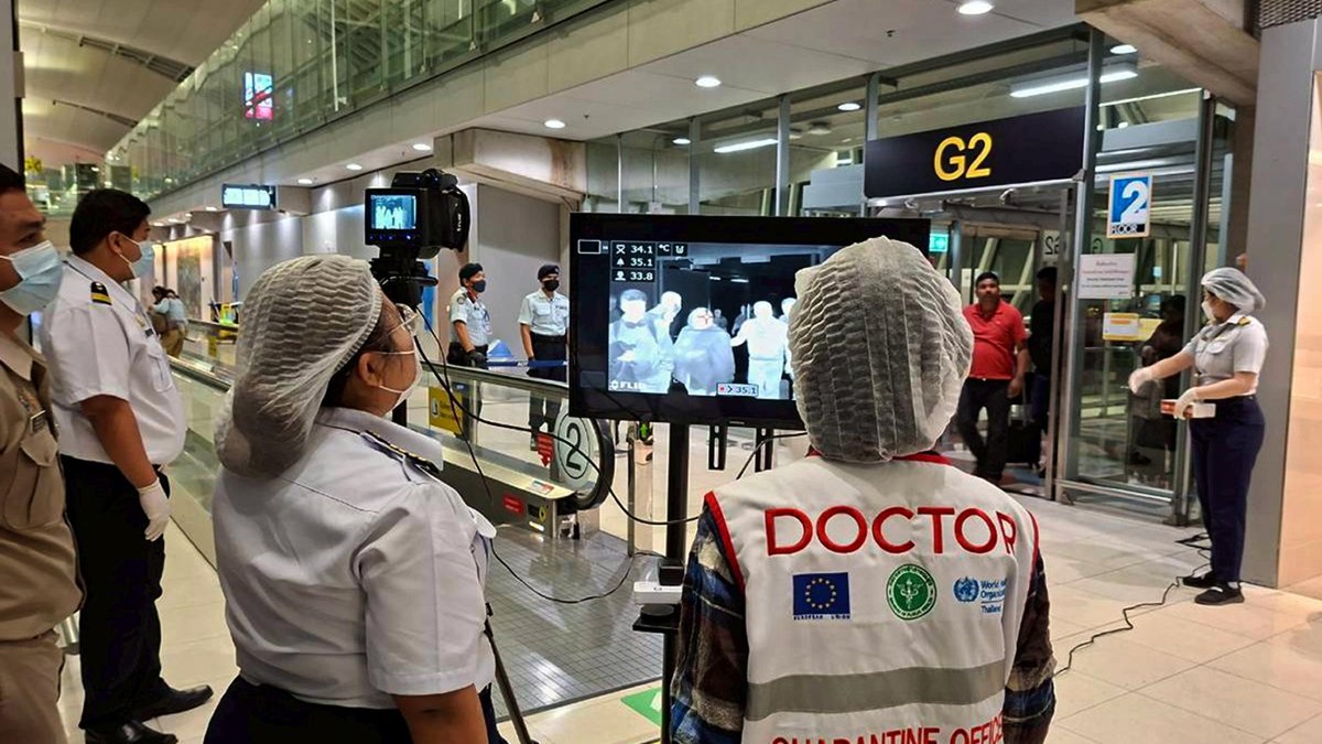 Foto distribuida por Suvarnabhumi Airport muestra a funcionarios de salud tailandeses usando mascarillas protectoras mientras monitorean a pasajeros de vuelos internacionales